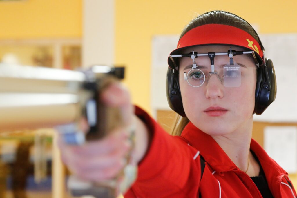 Eileen Schupper hält ihre Luftpistole im Anschlag und trägt eine Schießbrille, die ihr linkes Auge abdeckt.